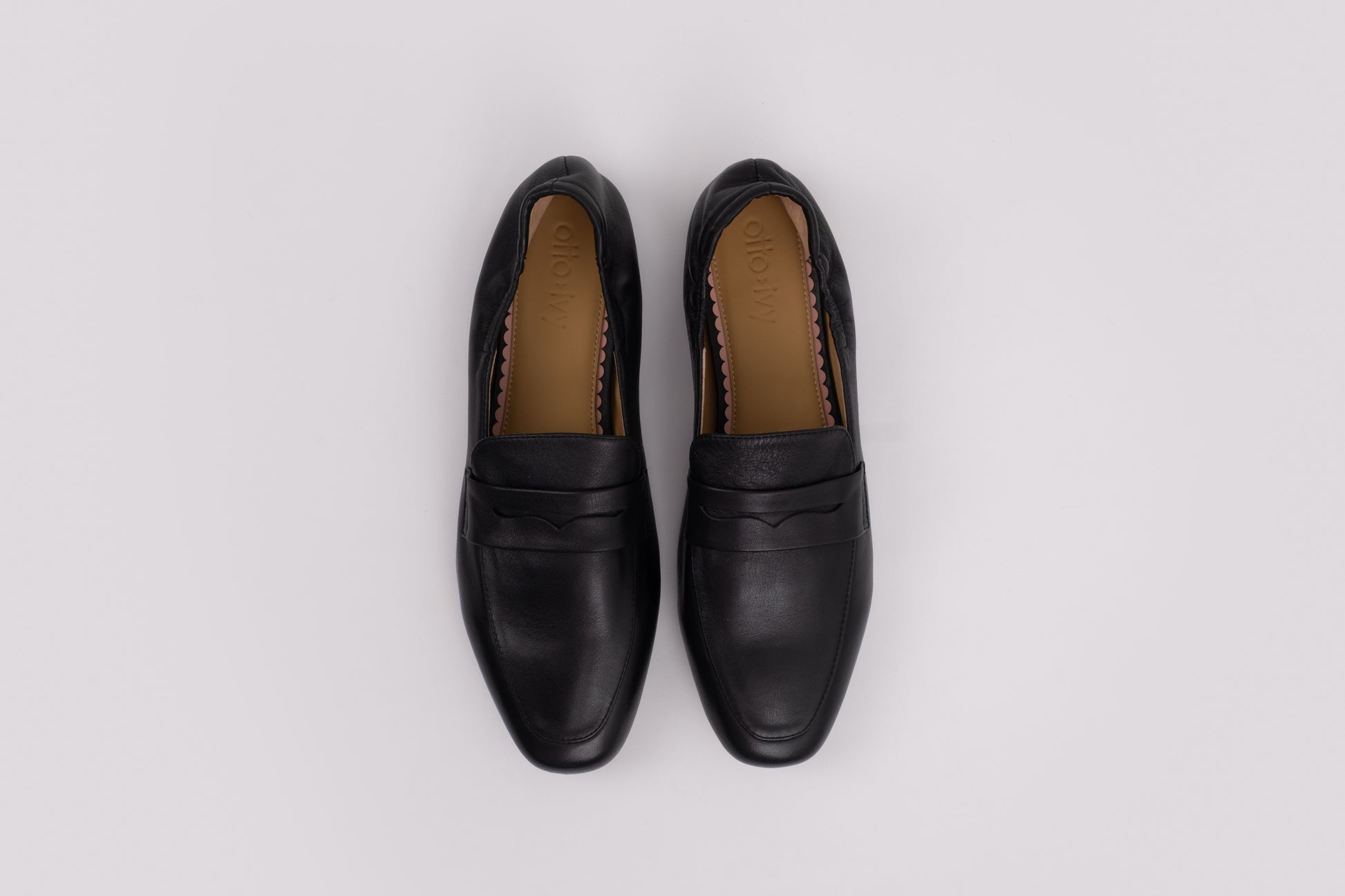 Pair of large size 9 black loafers on a light gray background
