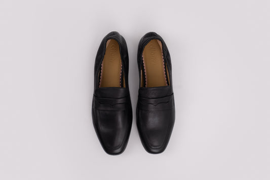 Pair of large size 9 black loafers on a light gray background