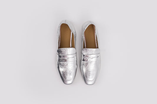 large sized 10 womens Pair of silver loafers on a light gray background