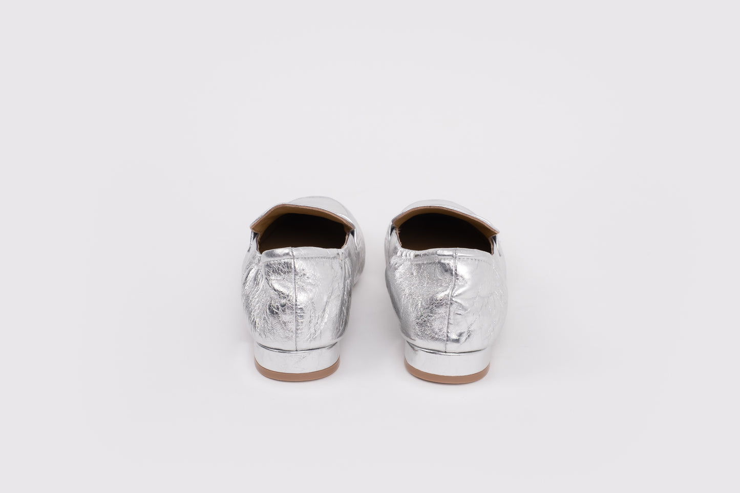 Large sized 9 womens Pair of silver metallic loafers on a white background
