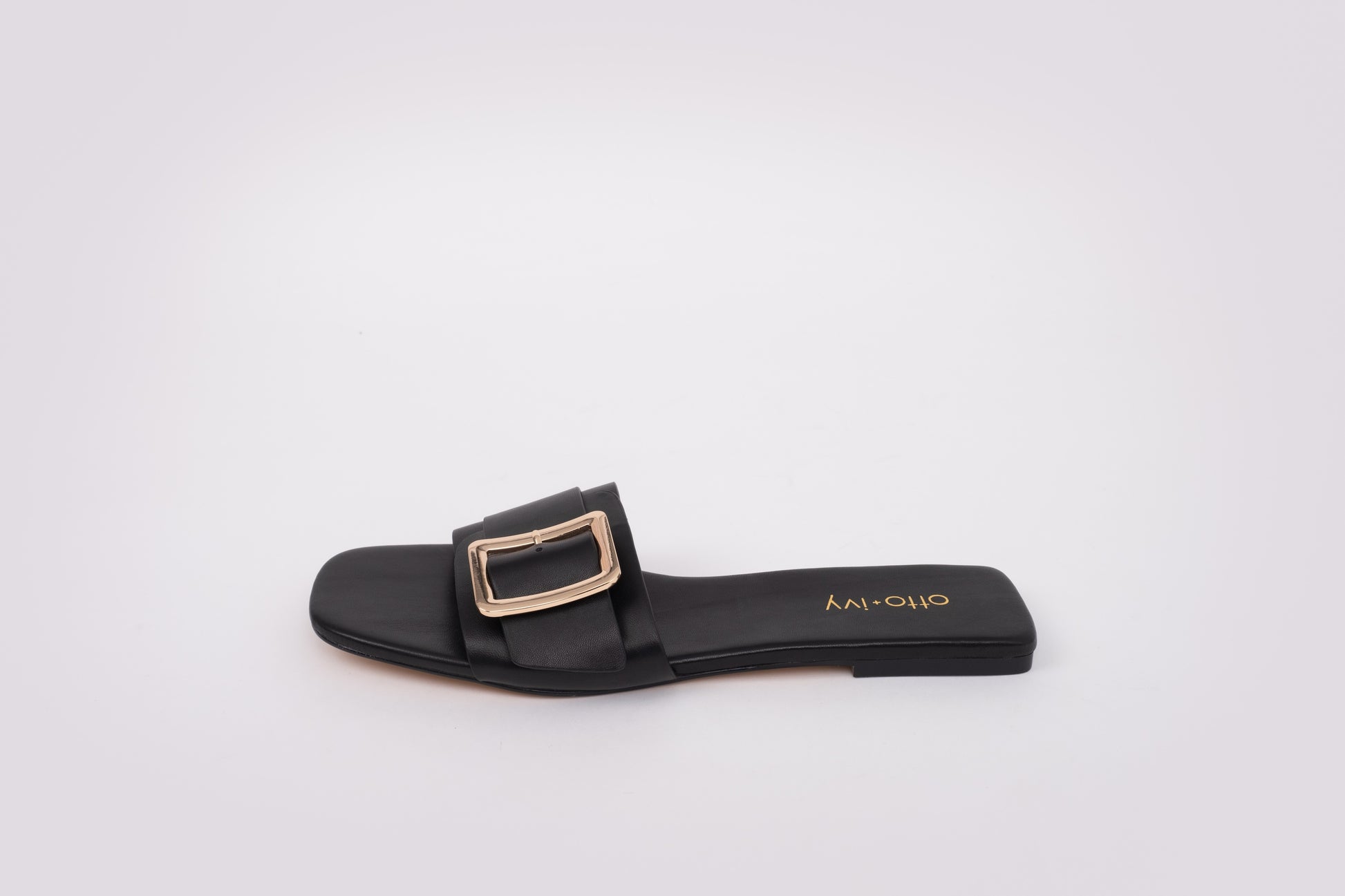 Side shot of Ruby in black. A womens slide on sandal with buckle detail Ava`iklable in larger sizes 42-46