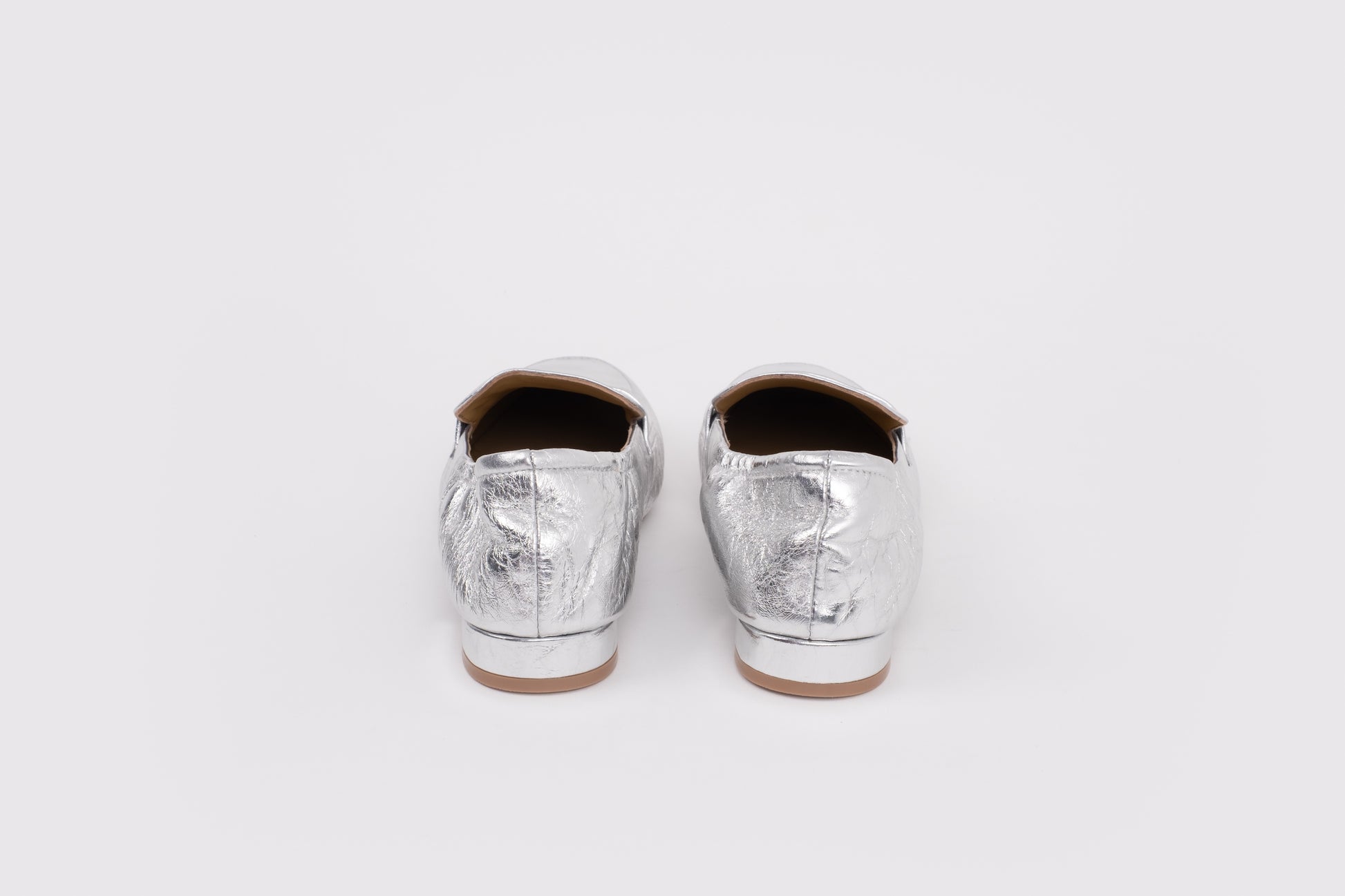 Large sized 9 womens Pair of silver metallic loafers on a white background