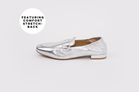 Large sized womens Silver loafer shoe on a white background with text 'Featuring Comfort Stretch'.